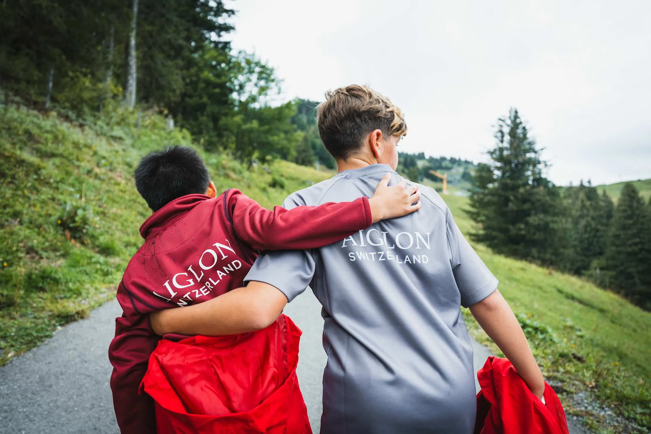 Dos alumnos de un internado en Suiza caminando abrazados por un sendero de montaña
